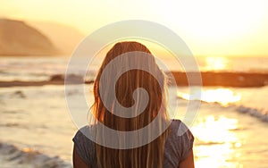 Mujer joven seguimiento atardecer sobre el Playa buscando sobre el el mar montanas en distancia. solo su cabeza a cabello 