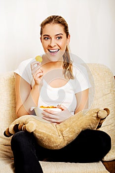 Young woman watching TV and eating chips