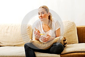 Young woman watching TV and eating chips