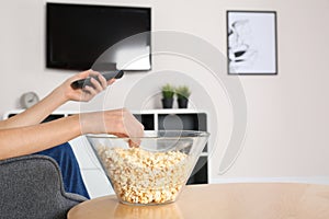 Young woman watching TV while eating popcorn