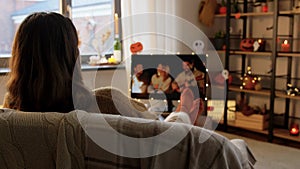 Young woman watching tv at home on halloween