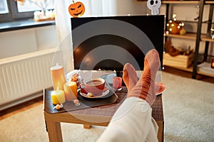 young woman watching tv at home on halloween