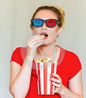 Young woman watching tv while sitting on a sofa with 3d glasses and popcorn with pleasure