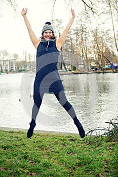 Young woman by the water jumping in the air