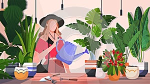 Young woman with watering can taking care of houseplants.