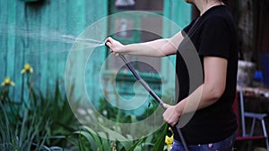 Young woman watering vegetable garden from hose. Close up of female watering. Concept of summer and garden care, organic products