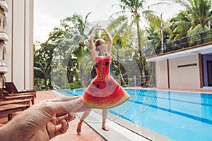 Young woman in a watermelon dress on a pool background. The concept of summer, diet and healthy eating