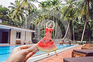 Young woman in a watermelon dress on a pool background. The concept of summer, diet and healthy eating