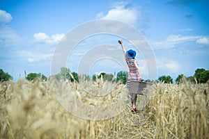Young woman waving hand to sky on summer wheat