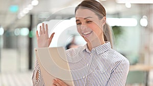 Young Woman Waving Hand for Video Chat on Tablet