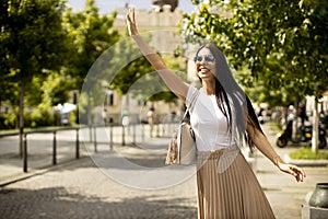 Young woman waving for a taxi on the street