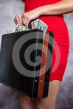 young woman wear red dress holding full dollars money bills in black briefcase