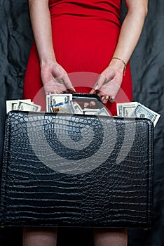young woman wear red dress holding full dollars money bills in black briefcase