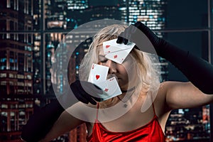 Young woman wear red shiny dress black hat holding cards of aces