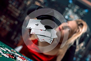 Young woman wear red shiny dress black hat holding cards of aces