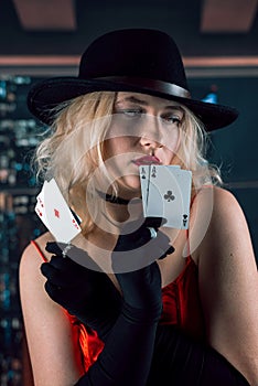 Young woman wear red shiny dress black hat holding cards of aces