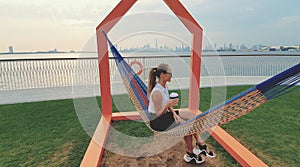 Young woman weared in office sute having coffee in hammock while chilling , freelance life style conceptual, work