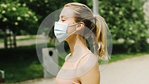 Young woman wearing antibacterial mask doing exercises in a city park.