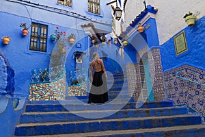 Young woman wearing a beautiful backless dress in Chefchaoun The Blue pearl, Morocco