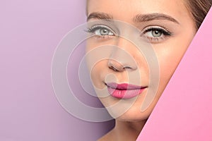 Young woman wearing beautiful lipstick on color background