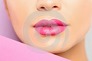 Young woman wearing beautiful lipstick on color background