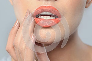 Young woman wearing beautiful lipstick on gray background