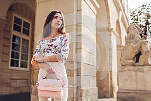 Young woman wearing beautiful outfit and accessories and shoes outdoors. Girl holding stylish handbag. Fashion model