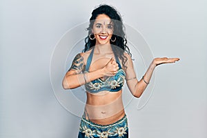 Young woman wearing bindi and traditional belly dance clothes showing palm hand and doing ok gesture with thumbs up, smiling happy