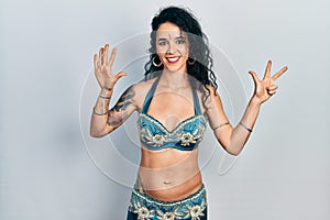Young woman wearing bindi and traditional belly dance clothes showing and pointing up with fingers number eight while smiling