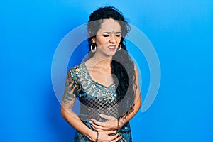 Young woman wearing bindi and traditional kurta dress with hand on stomach because nausea, painful disease feeling unwell