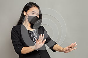 Young woman wearing black mask with both hands stopped