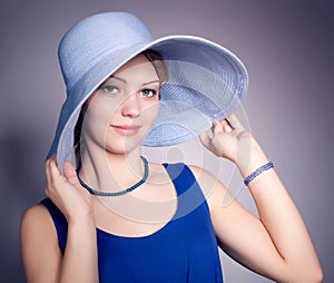 Young woman wearing blue dress and blue big hat