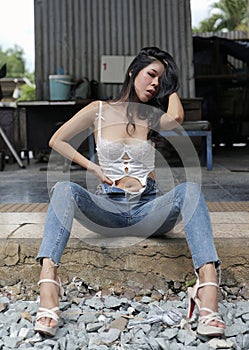 Young woman wearing blue jeans sits on the floor