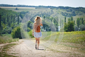 Young woman with a leather backpack on a summer rural road