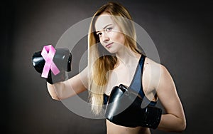 Young woman wearing boxing gloves having pink ribbon