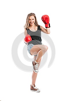 Young woman wearing boxing gloves and raising foot and hand