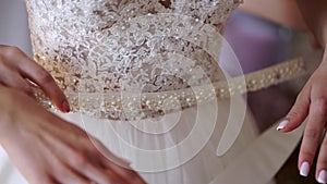 Young woman wearing bridal dress and put on belt