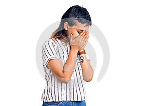 Young woman wearing casual clothes with sad expression covering face with hands while crying
