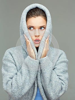 Young woman wearing coat hood sirprising.