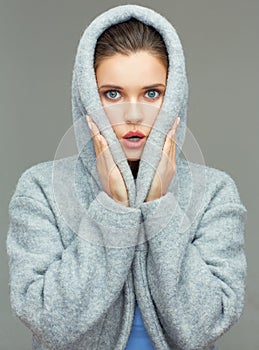 Young woman wearing coat hood sirprising.