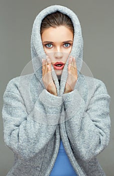 Young woman wearing coat hood sirprising.