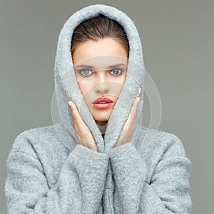 Young woman wearing coat hood sirprising