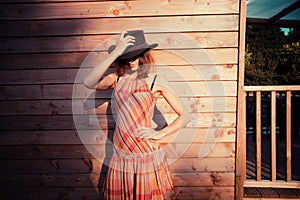 Young woman wearing cowboy hat by a cabin