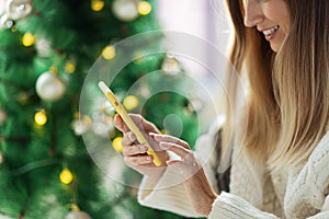 Young woman wearing cozy knitted sweater and red Santa hat when Paying online with credit card at home, holiday shopping