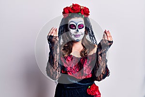 Young woman wearing day of the dead costume over white doing money gesture with hands, asking for salary payment, millionaire