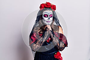 Young woman wearing day of the dead costume over white laughing nervous and excited with hands on chin looking to the side