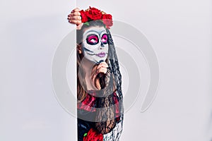 Young woman wearing day of the dead custome holding blank empty banner with hand on chin thinking about question, pensive