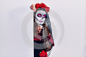 Young woman wearing day of the dead custome holding blank empty banner looking confident at the camera smiling with crossed arms