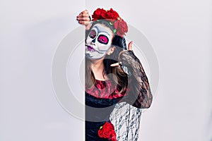 Young woman wearing day of the dead custome holding blank empty banner smiling doing phone gesture with hand and fingers like