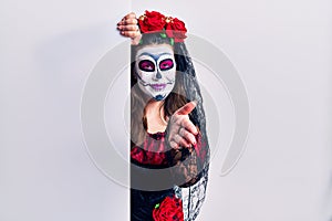 Young woman wearing day of the dead custome holding blank empty banner smiling friendly offering handshake as greeting and